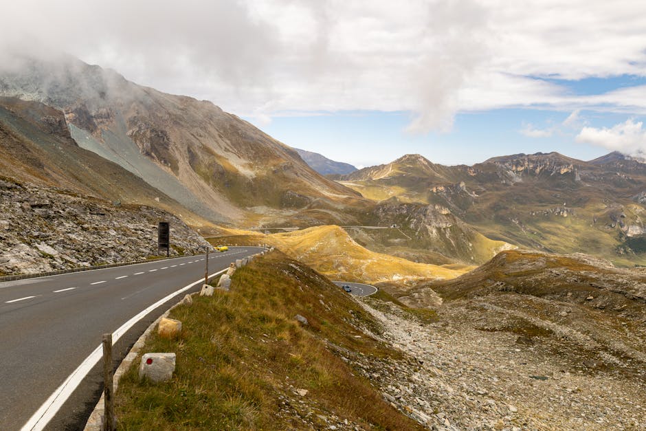 Breathtaking view of a winding road through the mountains in Hochtor, Austria, under a blue sky.